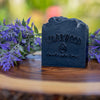Handmade bar Tea Tree Charcoal soap on wood surface surrounded by lavender flowers
